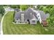 Aerial view of a brick home with a well-maintained lawn, landscaping, and neighboring pergola-covered deck at 15098 Newburyport Dr, Fortville, IN 46040