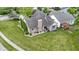 Aerial view of a brick home with a well-maintained lawn, landscaping, and neighboring pergola-covered deck at 15098 Newburyport Dr, Fortville, IN 46040