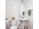Bathroom features a pedestal sink, toilet, mirror, and towel rack, all in a clean, minimalist design at 1521 Midnight Pass, Brownsburg, IN 46112