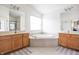 Bright bathroom with dual vanities, a large soaking tub, tile flooring, and modern fixtures at 1521 Midnight Pass, Brownsburg, IN 46112