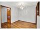 Open dining room with gleaming hardwood floors, stylish chandelier, and natural light flowing through an open doorway at 3322 N Riley N Ave, Indianapolis, IN 46218
