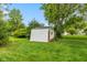 Backyard shed on a lush green lawn beneath a clear blue sky, surrounded by trees at 3388 S Leonard Rd, New Palestine, IN 46163