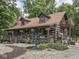 Charming log home with wraparound porch, second story balcony, and lovely landscaping with mature trees at 5240 W 400 N, Fairland, IN 46126