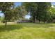 Expansive backyard featuring mature trees, a storage shed, firepit, and a glimpse of the home's exterior at 540 Lazy Ln, Greenwood, IN 46142