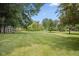 Large, meticulously maintained backyard with mature trees and a firepit, offering ample green space at 540 Lazy Ln, Greenwood, IN 46142