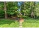 Secluded backyard featuring mature trees, a gravel path, and a charming storage shed at 5424 Broadway St, Indianapolis, IN 46220