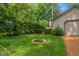 Fenced backyard showing a built-in fire pit and lush green landscaping, perfect for outdoor enjoyment at 5424 Broadway St, Indianapolis, IN 46220
