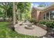 A brick home featuring a brick patio with fire pit, a green lawn, and mature trees at 5997 Hollythorn Pl, Carmel, IN 46033