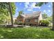 A sprawling backyard with lush green grass and mature trees adjacent to a brick home and patio at 5997 Hollythorn Pl, Carmel, IN 46033