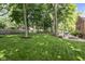 A lush backyard with mature trees, green grass, and a brick fire pit at 5997 Hollythorn Pl, Carmel, IN 46033
