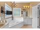 Bathroom with a bathtub, window, mounted television, vanity, and chandelier at 5997 Hollythorn Pl, Carmel, IN 46033