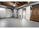 Unfinished basement with painted floors, exposed ceiling, white brick walls, and wooden stairs at 6146 Burlington Ave, Indianapolis, IN 46220