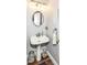 Charming powder room with pedestal sink, decorative mirror, and wood-look tile floors at 7755 Dayflower Ct, Noblesville, IN 46062