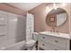 Stylish pink bathroom featuring a round mirror, a single vanity, and a shower-tub combo at 8140 Bold Forbes Ct, Indianapolis, IN 46217