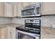 Kitchen showcases granite counters, white cabinets, stainless steel stove, and overhead microwave at 8140 Bold Forbes Ct, Indianapolis, IN 46217