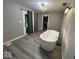 Bright bathroom featuring a modern soaking tub near a glass paneled door and modern light fixture at 8407 Campbell Ct, Mooresville, IN 46158