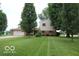 Inviting front yard view of home with a manicured lawn, mature trees, and attached two-car garage at 8905 Maze Rd, Indianapolis, IN 46259