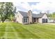 Charming house with a stone chimney, green lawn, colorful flowers, and a lovely landscape at 8925 Sunburst Cir, Indianapolis, IN 46227