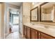 Bathroom featuring a double vanity with warm cabinets and two mirrors, leading into another room at 9237 Rocky Cay Ct, Zionsville, IN 46077