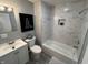 Modern bathroom with sleek vanity, toilet, and combined bathtub/shower with marble tile at 937 N Routiers Ave, Indianapolis, IN 46219