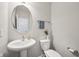 Powder room with pedestal sink, round mirror and stylish neutral decor at 9707 Prairie Smoke Dr, Noblesville, IN 46060