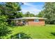 Charming single-story brick home with a metal roof and lush green lawn on a sunny day at 10159 Hodge Rd, Clayton, IN 46118
