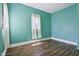 Simple bedroom with teal walls, wood floors, and window with curtains at 1129 Trowbridge St, Indianapolis, IN 46203