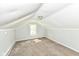 Attic features neutral carpet, slanted ceilings, one window, and light fixture at 114 South St, Southport, IN 46227