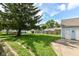 Backyard featuring a large pine tree, grass lawn, and privacy fence at 114 South St, Southport, IN 46227