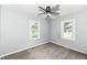 Sunlit bedroom features a ceiling fan and two windows offering views of the outside at 114 South St, Southport, IN 46227