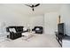 A well-lit living room featuring a black sofa, loveseat, white coffee table, ceiling fan and neutral carpet at 12490 Windbush Way, Carmel, IN 46033