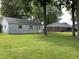 View of the backyard with a detached garage, mature trees and a large lawn at 1400 Evelyn Ln, Anderson, IN 46017