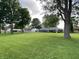 View of the backyard with mature trees, large lawn and home at 1400 Evelyn Ln, Anderson, IN 46017