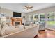 Inviting living room with fireplace, hardwood floors, a ceiling fan, and ample natural light at 15075 Windsor Ln, Noblesville, IN 46060