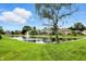 A tranquil pond with a fountain surrounded by lush greenery and mature trees in the backyard at 182 Southwind Ln, Greenwood, IN 46142