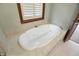 Soaking tub in bathroom with natural light from a window featuring privacy shutters at 182 Southwind Ln, Greenwood, IN 46142