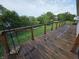 Wooden deck with a railing overlooking a yard with a creek and mature trees at 21 Watson Dr, Trafalgar, IN 46181