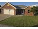 Charming red brick home with a two-car garage, green lawn, and landscaped garden bed at 21 Watson Dr, Trafalgar, IN 46181