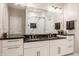 Bathroom vanity with double sinks, black countertop, and a large mirror reflecting a tiled shower with glass doors at 225 N New Jersey St # 52, Indianapolis, IN 46204