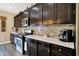 A well-appointed kitchen featuring dark wood cabinets, stone backsplash, stainless steel appliances, and light countertops at 2282 Creekland Dr, Columbus, IN 47201