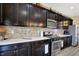 The kitchen features dark wood cabinets, stainless steel appliances, stone backsplash, and ample countertop space at 2282 Creekland Dr, Columbus, IN 47201