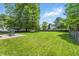 Expansive backyard featuring a lush green lawn, mature trees, and a patio with outdoor furniture at 2463 Kettering Way, Indianapolis, IN 46214