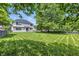 Spacious backyard featuring a well-maintained lawn, mature trees, and a charming two-story home at 2463 Kettering Way, Indianapolis, IN 46214