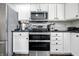Galley kitchen with stainless steel appliances, subway tile backsplash, white cabinetry, and dark countertops at 2463 Kettering Way, Indianapolis, IN 46214