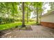 Lush backyard features mature trees and landscaping, extending from the brick patio at 2613 W Queensbury Rd, Muncie, IN 47304