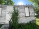 Close up of a dilapidated house with boarded windows, peeling paint and overgrown yard at 2625 E 12Th St, Indianapolis, IN 46201