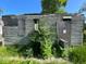 Exterior view of the side of a dilapidated house with boarded windows and overgrown yard at 2625 E 12Th St, Indianapolis, IN 46201