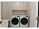 Efficient laundry room with front loading washer and dryer and overhead cabinets for storage at 2734 Chalbury Dr, Plainfield, IN 46168