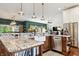 Open-concept kitchen featuring granite countertops, a farmhouse sink, stainless appliances, and wood cabinets at 3399 Nottinghill Blvd, Plainfield, IN 46168