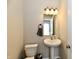 Bathroom with a pedestal sink, toilet, and decorative mirror with updated light fixture at 3443 Thomas Jefferson St, Westfield, IN 46074